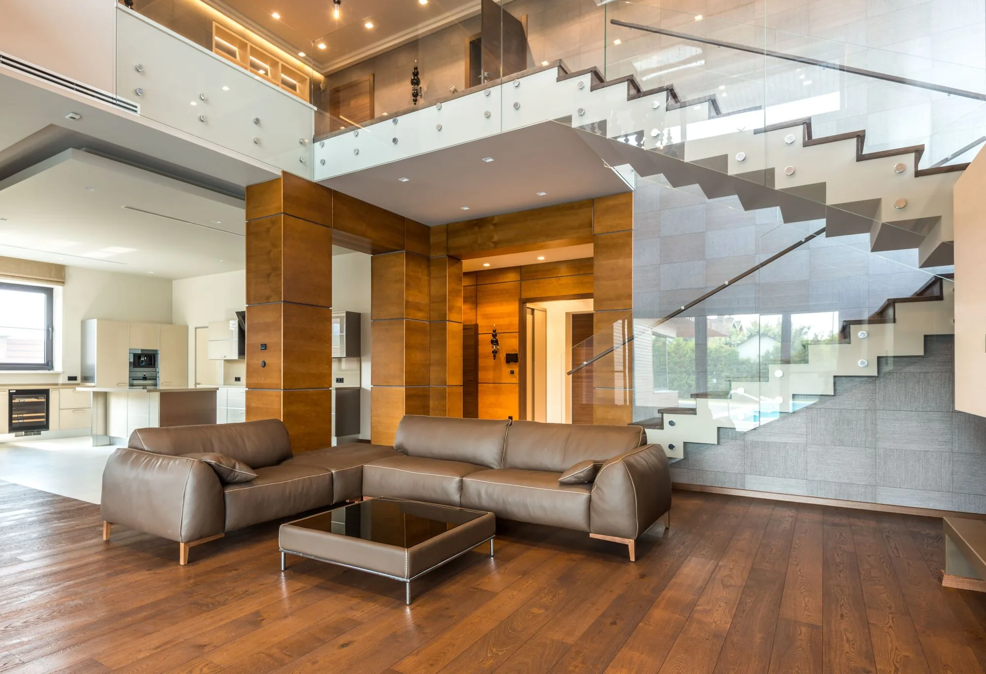 Salón a doble altura con escalera de cristal y madera