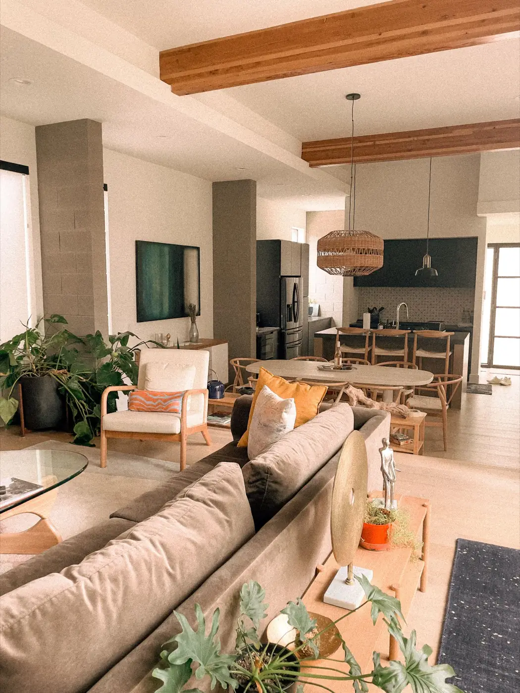 Salón comedor abierto a la cocina, con vigas de madera vista y mobiliario en tonos claros