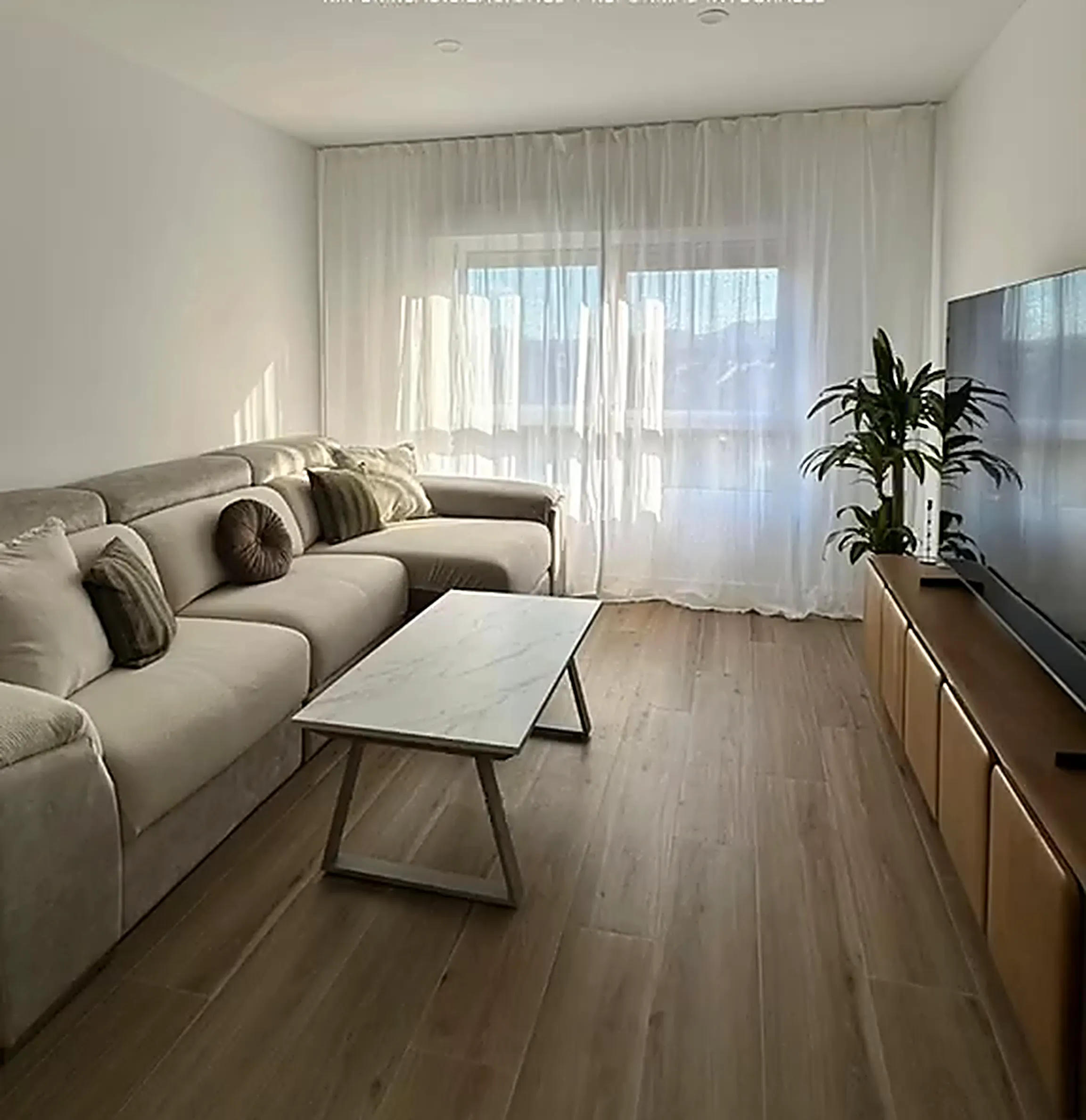 Salón terminado con sofá, cortinas y suelo laminado